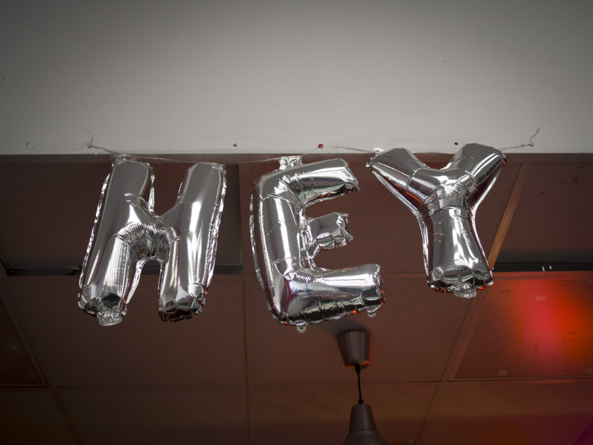 Three silver balloons say H E Y