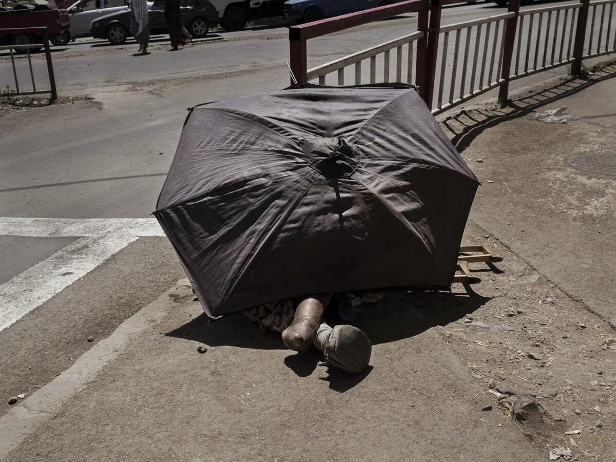 Barefoot feet are coming out from under the tattered umbrella